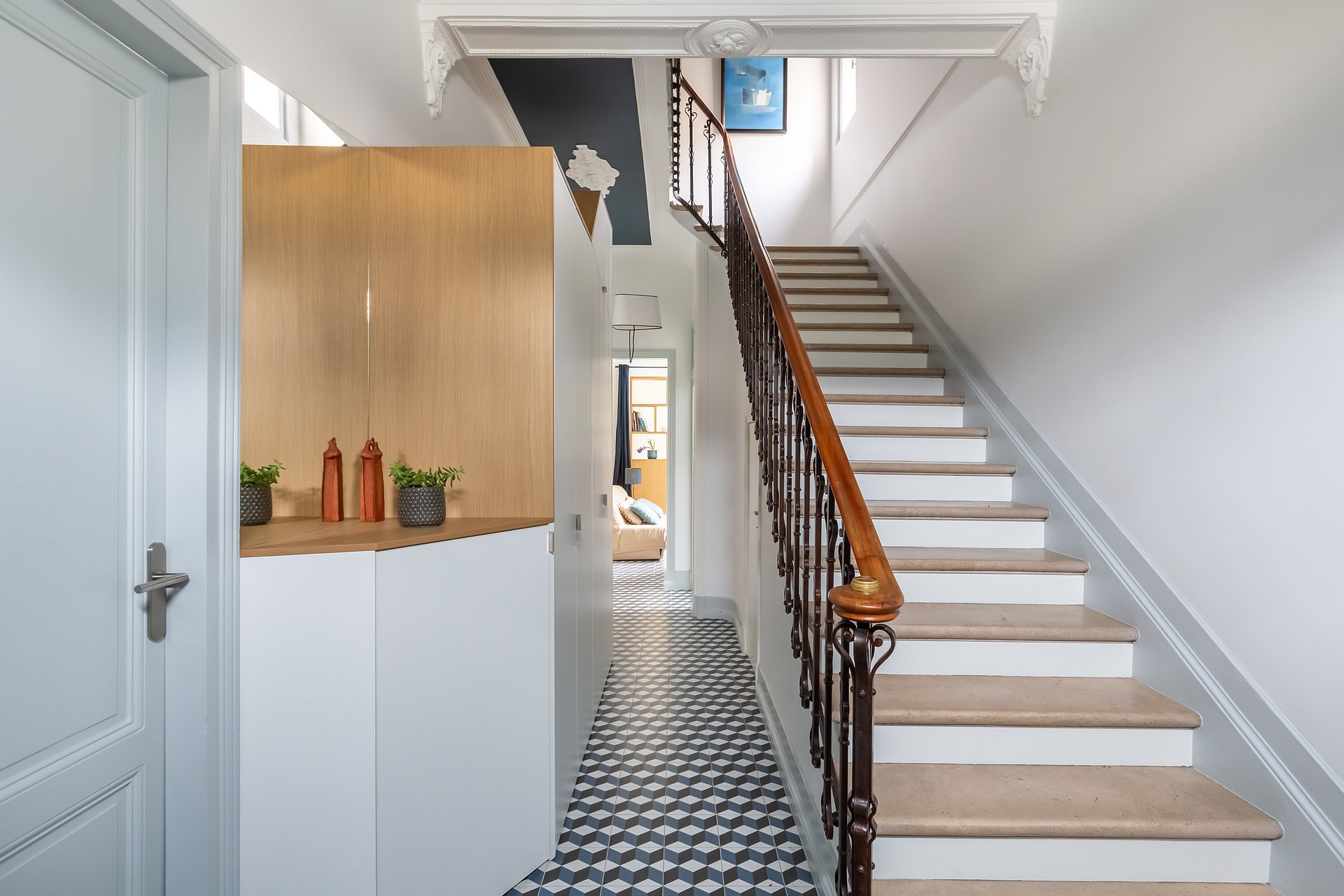 Escalier en bois et métal avec rampe en fer forgé, plafond bleu nuit et moulures élégantes.
