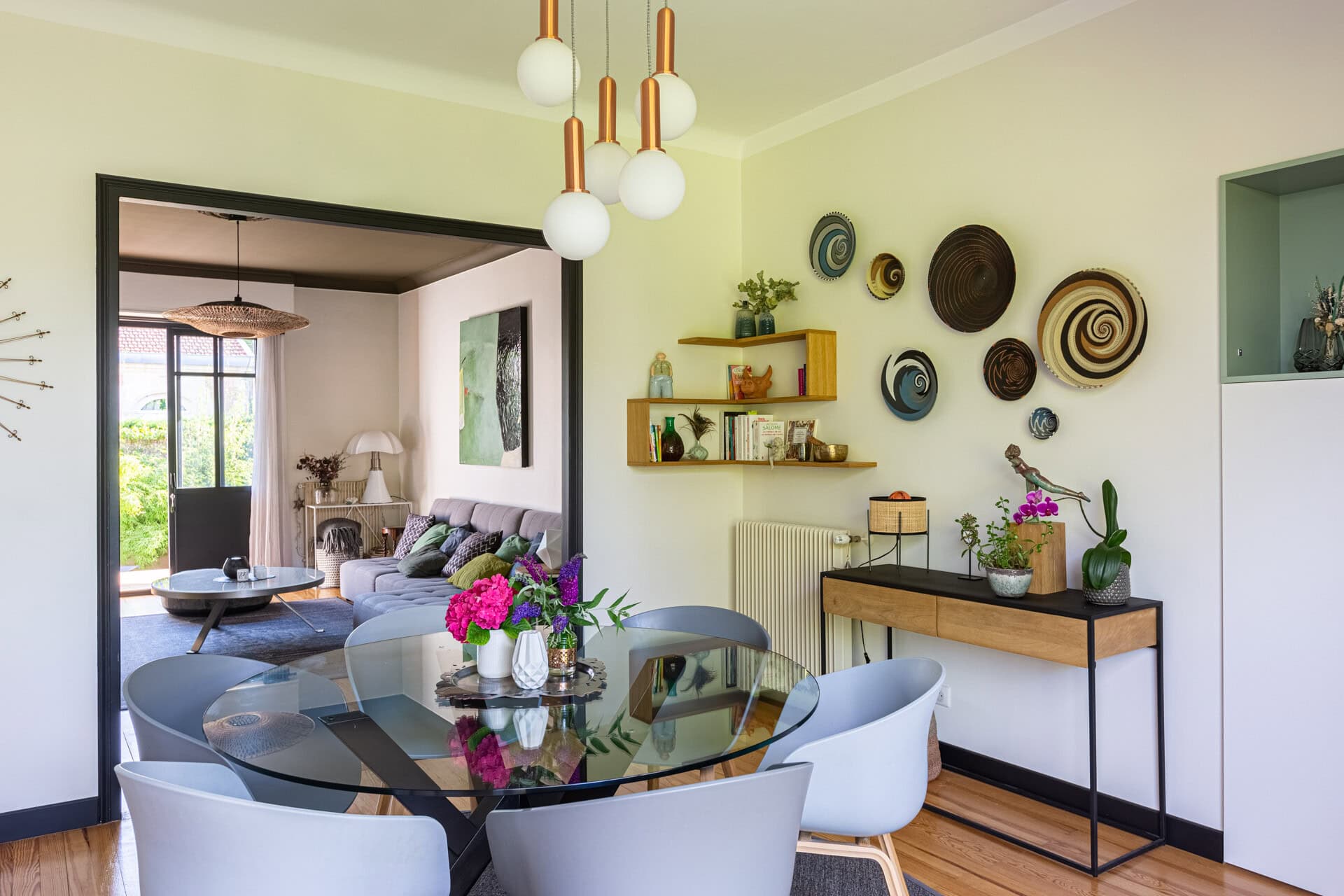 Salle à manger avec décoration murale et vue sur un salon lumineux