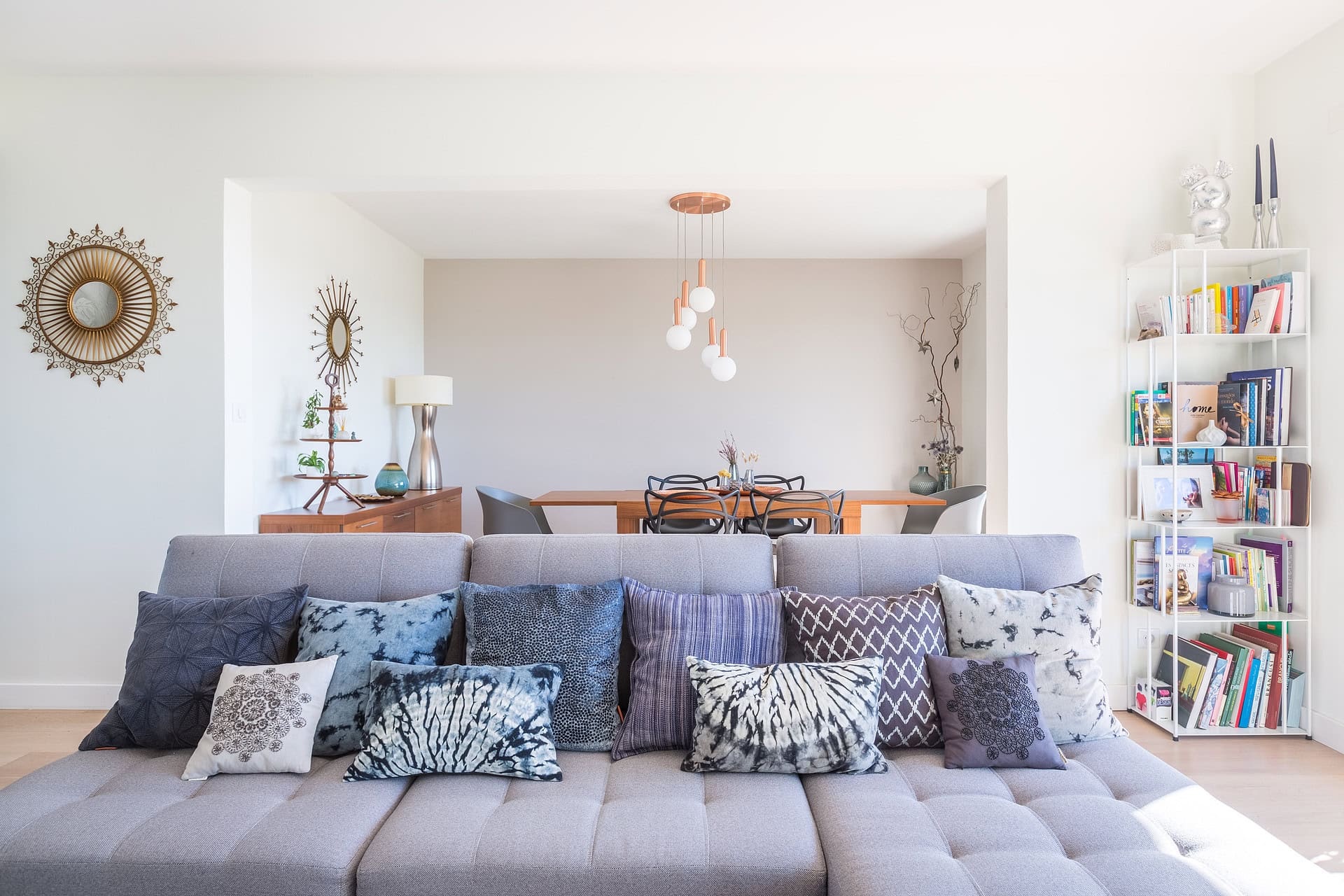Salon moderne avec un canapé gris et des coussins aux motifs variés
