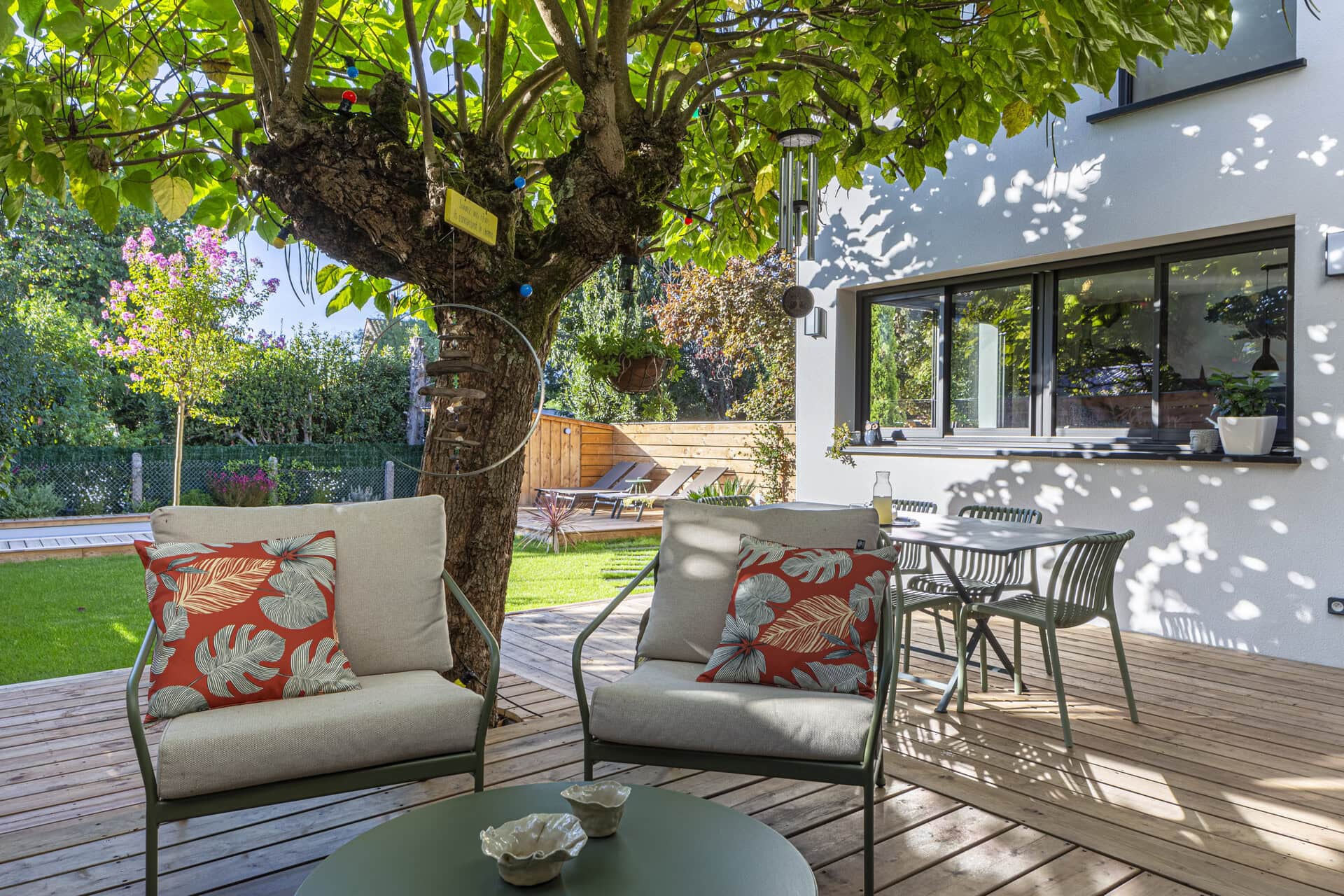 Terrasse en bois aménagée avec salon extérieur et vue sur le jardin et la piscine.